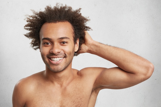 Disparo en la cabeza del atractivo chico afroamericano con peinado tupido, desnudo, contento de tener deporte
