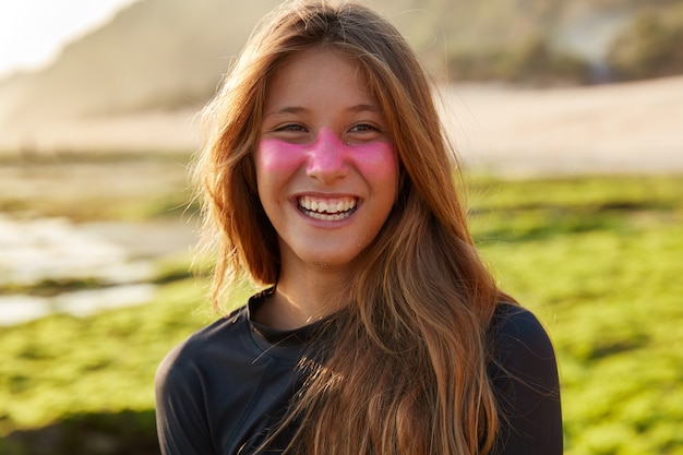 Disparo en la cabeza de encantadora mujer complacida con cabello largo, sonrisa con dientes