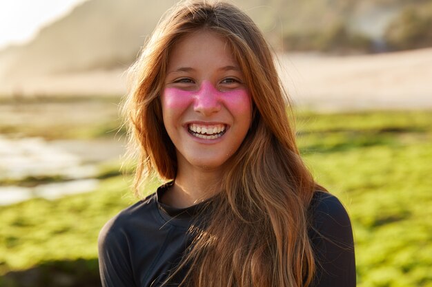 Disparo en la cabeza de encantadora mujer complacida con cabello largo, sonrisa con dientes