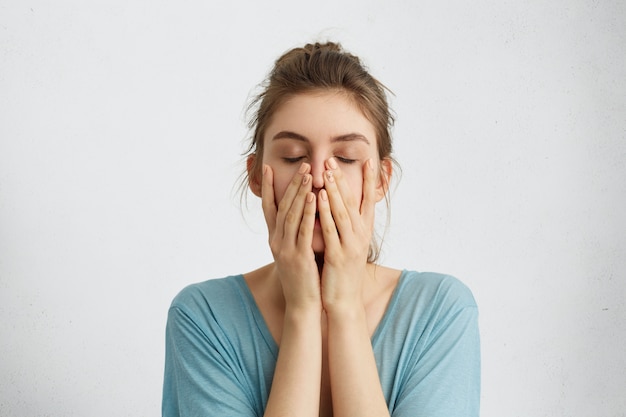 Foto gratuita disparo en la cabeza de la joven hermosa mujer cerrando los ojos tomados de la mano en la barbilla está cansado