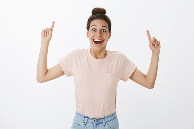 Disparo de cintura para arriba de la joven novia feliz sorprendida entusiasta encantada en camiseta casual levantando las manos para señalar sonriendo emocionado