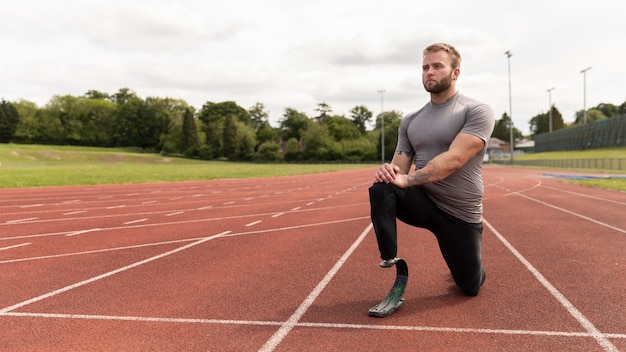 Disparo completo hombre discapacitado en pista de atletismo estiramiento