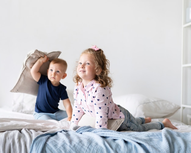 Foto gratuita disparo completo niños sentados en el dormitorio