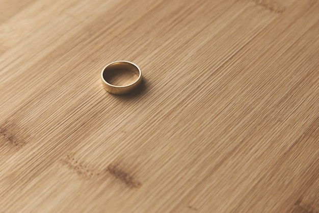 Foto gratuita disparo de enfoque selectivo de un anillo de bodas de oro sobre una superficie de madera