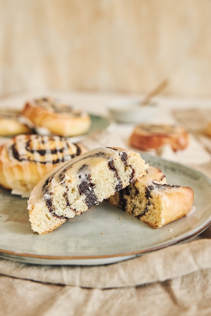 Foto gratuita disparo de enfoque selectivo de deliciosos rollos de semillas de amapola con un glaseado de azúcar sobre una mesa