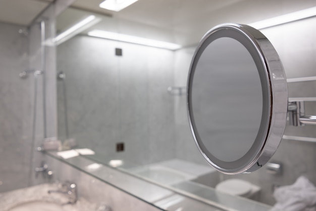 Foto gratuita disparo de enfoque selectivo del espejo en el baño con interior blanco