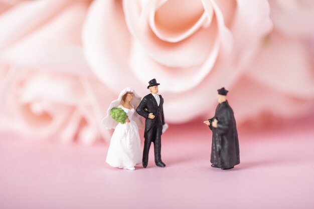 Disparo de enfoque selectivo de figurillas en miniatura de la novia, el novio y el sacerdote