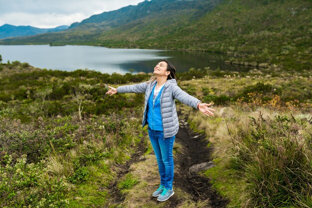 Disparo de enfoque selectivo de una hermosa joven disfrutando de la naturaleza cerca de un lago