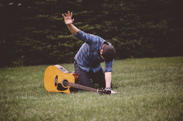 Foto gratuita disparo de enfoque selectivo de un hombre emocional afuera con su guitarra