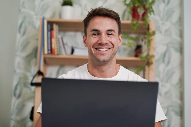 Disparo de enfoque selectivo de un hombre guapo sonriendo y trabajando con una computadora portátil