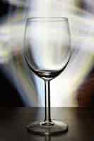 Foto gratuita disparo de enfoque selectivo vertical de una copa de vino vacía con luces borrosas