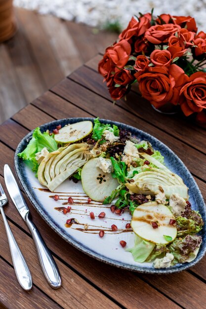 Disparo de enfoque selectivo vertical de ensalada de verduras en la mesa de madera