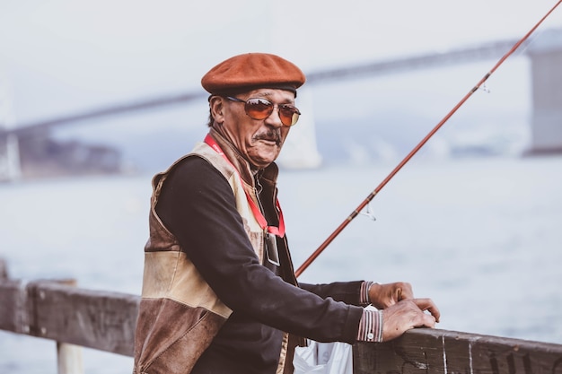 Foto gratuita disparo de enfoque superficial de un anciano con una caña de pescar