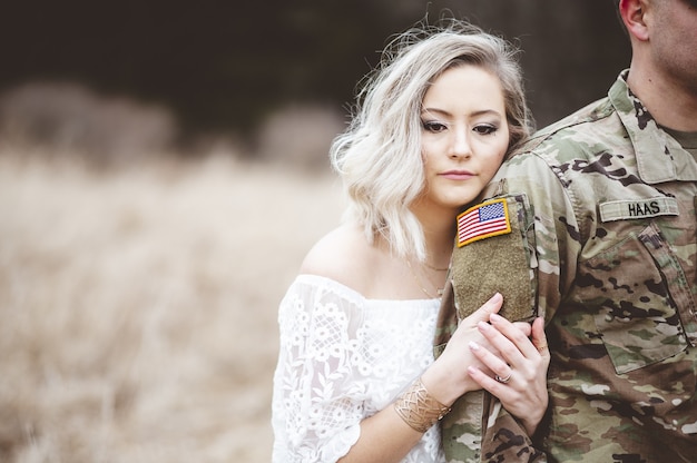 Foto gratuita disparo de enfoque superficial de una atractiva mujer sosteniendo el brazo de un soldado americano