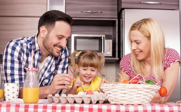 Disparo de enfoque superficial de una familia feliz pintando huevos de Pascua con alegría