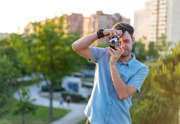 Disparo de enfoque superficial de un hombre joven tomando una foto en el parque