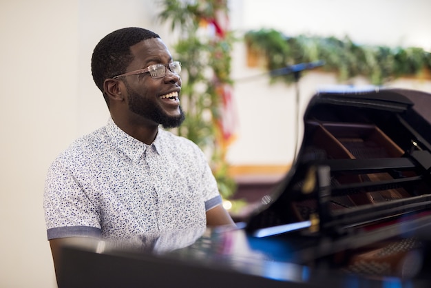 Foto gratuita disparo de enfoque superficial de un hombre sonriendo mientras toca el piano