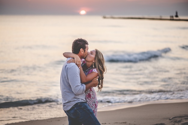 Disparo de enfoque superficial de una joven pareja encantadora besándose en la playa