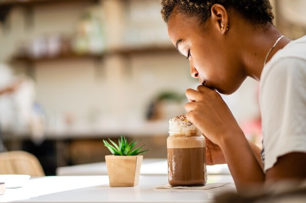 Un disparo de enfoque superficial de una mujer afroamericana bebiendo batido