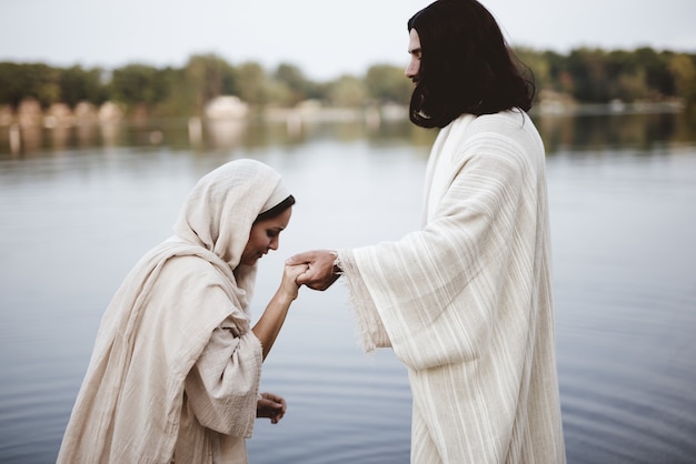 Disparo de enfoque superficial de una mujer vistiendo una bata bíblica mientras sostiene la mano de Jesucristo