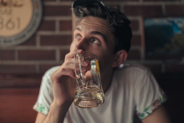 Foto gratuita disparo de enfoque superficial de una persona sosteniendo un vaso de cerveza vacío