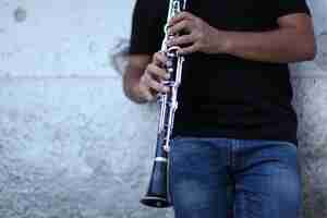 Foto gratuita disparo de enfoque superficial de una persona tocando el clarinete delante de una pared blanca