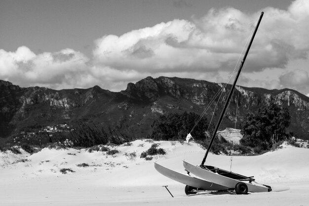 Disparo en escala de grises de una canoa de vela sobre ruedas en montañas nevadas