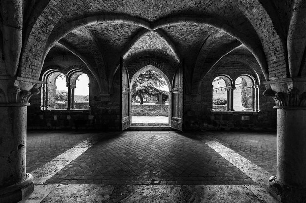 Disparo en escala de grises dentro de la abadía de San Galgano en Toscana Italia con diseño de paredes de arco