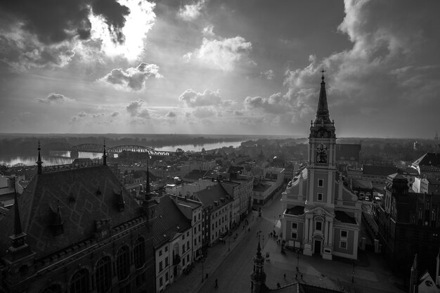 Disparo en escala de grises de edificios en la ciudad de Torun en Polonia con un cielo nublado en el fondo