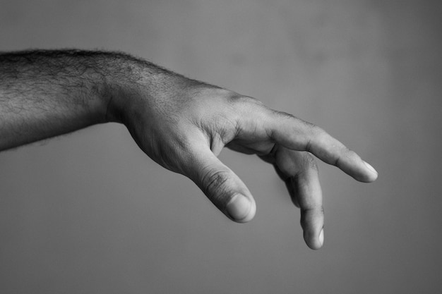 Foto gratuita disparo en escala de grises de una mano masculina mostrando un gesto