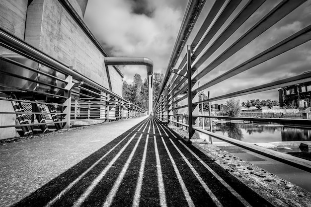 Foto gratuita disparo en escala de grises de un puente bajo un cielo nublado