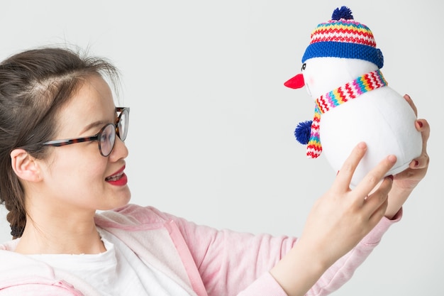 Disparo en el estudio de la joven mujer asiática sosteniendo un muñeco de nieve de Navidad