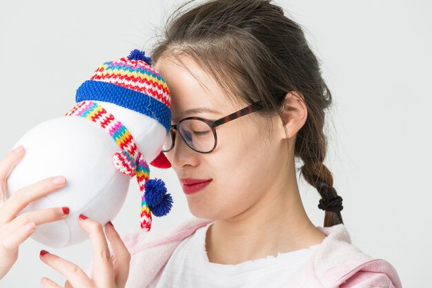 Disparo en el estudio de la joven mujer asiática sosteniendo un muñeco de nieve de Navidad