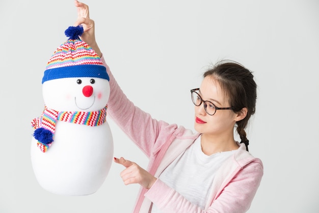 Foto gratuita disparo en el estudio de la joven mujer asiática sosteniendo un muñeco de nieve de navidad