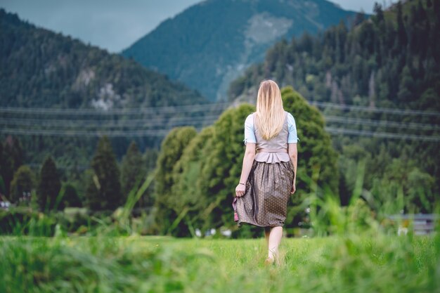 Disparo gran angular de una mujer vestida con una falda y corbata caminando hacia las montañas