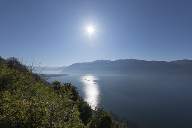 Disparo de gran angular del sol brillando sobre el agua y las montañas