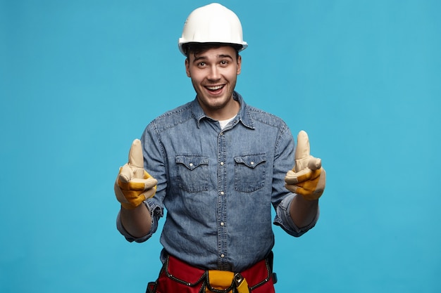 Disparo horizontal de atractivo joven constructor masculino sin afeitar con casco de seguridad