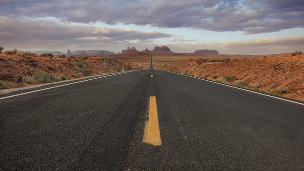 Disparo horizontal de una carretera vacía en el Monument Valley, EE.UU. con el fondo del cielo impresionante