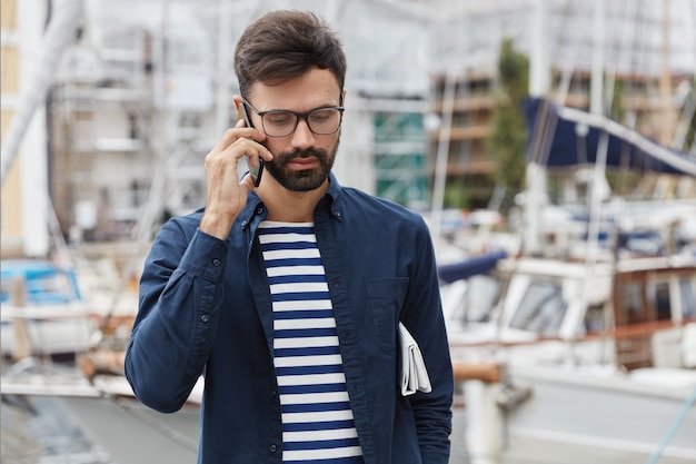 Disparo horizontal de chico pensativo está hablando por teléfono