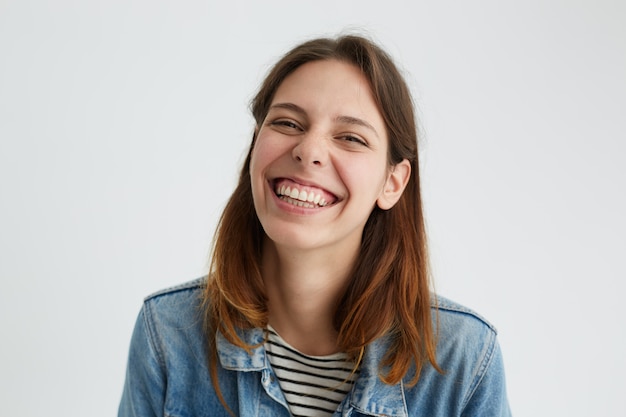 Disparo horizontal de juguetona hermosa joven de buen humor con alegre mirada alegre, sonriendo felizmente, disfrutando de un buen día. Emociones humanas positivas