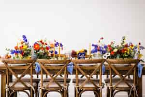 Foto gratuita disparo horizontal de una mesa con sillas de madera decoradas con velas y flores de colores