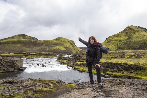 Disparo horizontal de una mujer caucásica con mochila de trekking en Landmannalaugar, Islandia