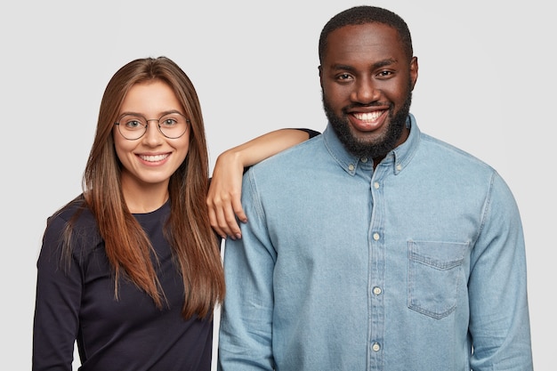 Foto gratuita disparo horizontal de pareja de raza mixta de pie muy cerca uno del otro, estando de buen humor