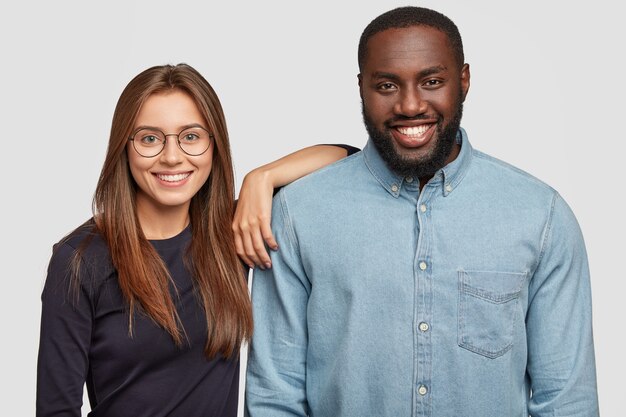 Disparo horizontal de pareja de raza mixta de pie muy cerca uno del otro, estando de buen humor