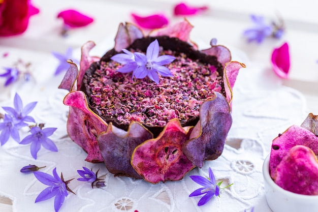 Disparo horizontal de un pastel morado vegano crudo de pera con peras deshidratadas sobre una mesa blanca