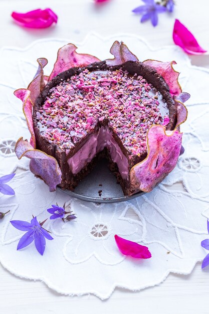 Disparo horizontal de un pastel púrpura vegano crudo de pera cortada con peras deshidratadas sobre una mesa blanca