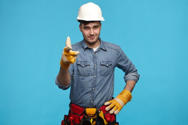 Disparo horizontal de trabajador de servicio de mantenimiento joven guapo con casco blanco