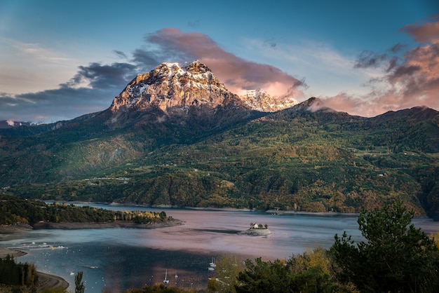 Disparo idílico de una enorme montaña cubierta de vegetación con un cuerpo de agua en su base