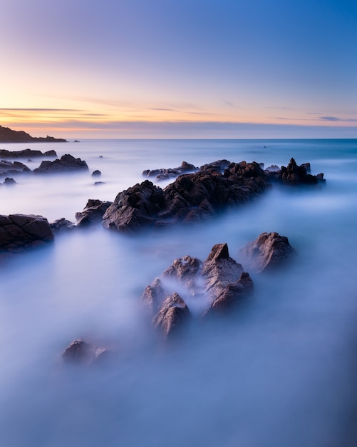 Disparo de larga exposición vertical del paisaje marino en Guernsey durante la puesta de sol