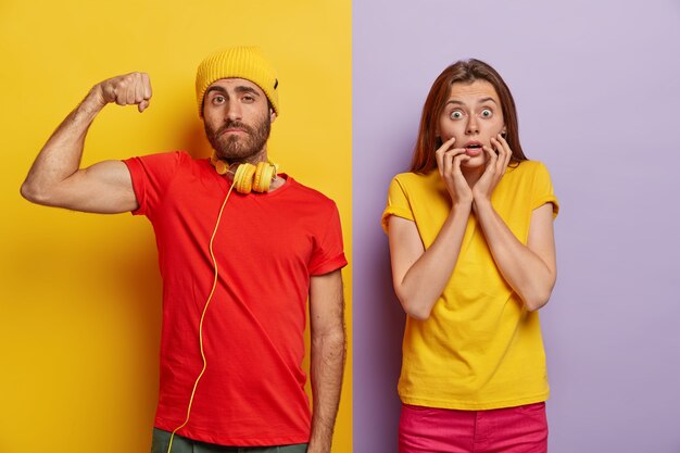 Disparo de media longitud de la atractiva pareja milenaria posando contra la pared de dos colores